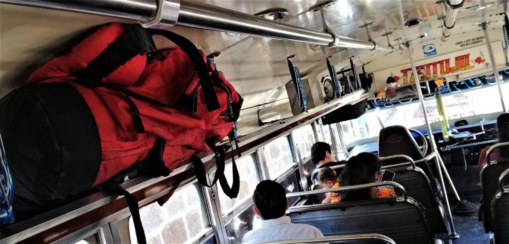 People and a red backpack inside a public transportation bus in Quetzaltenango, Guatemala.  From the Post: Refurbished Former US School Buses: The Pulse of a Nation.