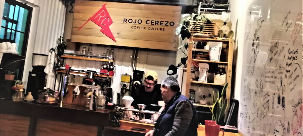 The scene inside Rojo Cerezo Coffee Culture.  A patron looks on while the barista labels bags filled with freshly roasted beans.  From the post: Guatemala City: A Terrific Travel Destination.