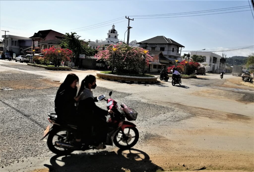A roundabout and four motorcycles being ridden during the day time. From the post: Luang Namtha: Why I Spent a Week in a Virtual Ghost Town.