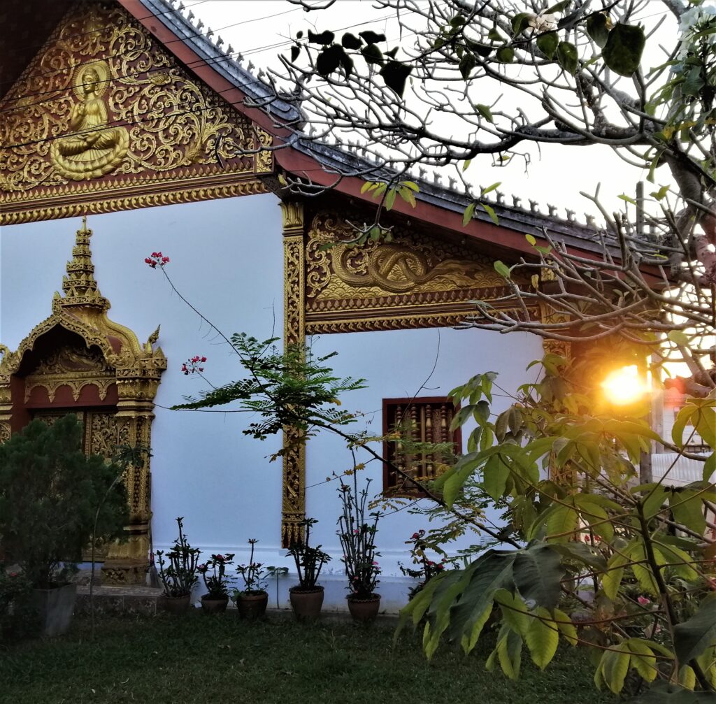 The end of day sun peers brightly beside a piece of dazzling religious architecture. In the post: Infinite Earth Art: Temples of Luang Prabang.