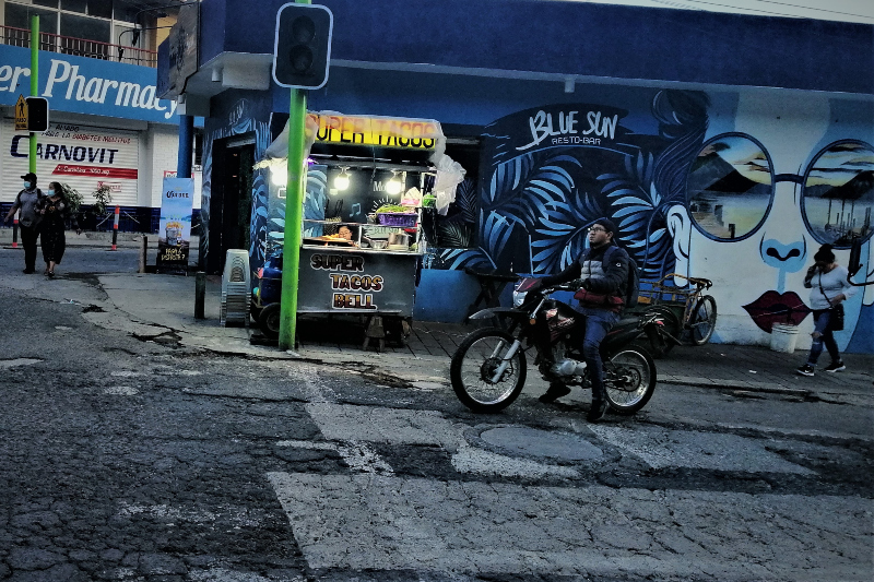 Street scene Panajachel.  A biker, graffiti, pavement and Super Tacos that provide excellent street food.