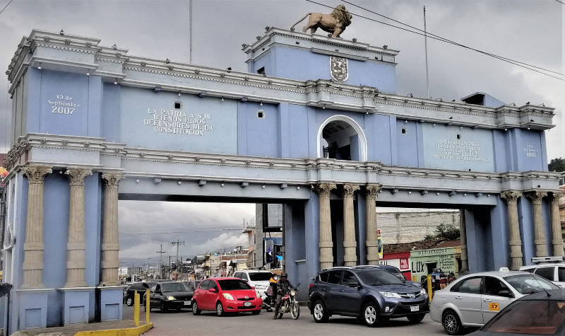 The big blue arch and traffic underneath on a gray day in Quezaltenango, Guatemala.  Journey to Fuentes Georgina Post.
