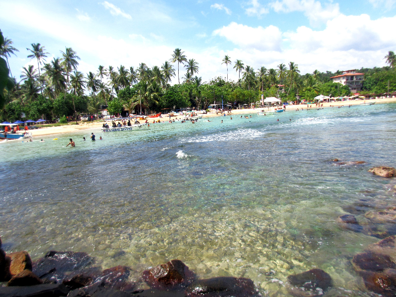 Reflection, beach, people, sand, and trees on Unawatuna Beach, Sri Lanka.