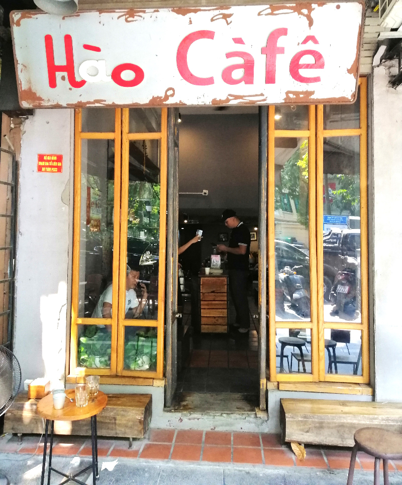 Small façade, with a view of two people inside, Hao Cafe, Hanoi, Vietnam. 