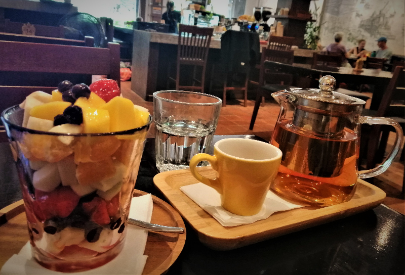 Big glass of mixed fruit, glass of water, mug, and pot full of white tea inside Naked Espresso Mixay, Vientiane, Laos.