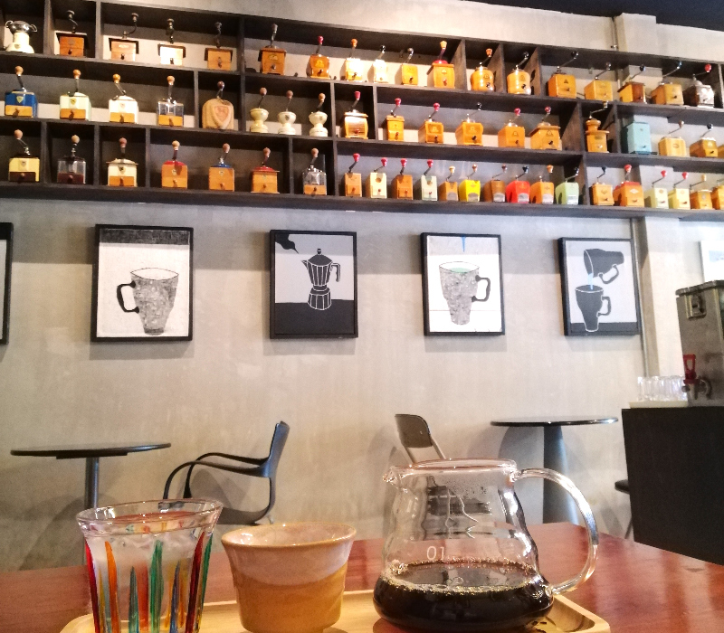 Drip coffee, framed coffee art on the wall and three shelves of coffee grinders imported from Germany inside 2Kaffee, Khon Kaen, Thailand. 