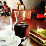 Pour over coffee, green tea chocolate cake and people inside Brown Coffee, Siem Reap, Cambodia