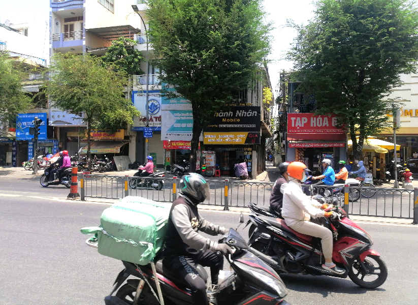 Scooters, a street and businesses during daylight, in Ho Chi Min City, Vietnam.