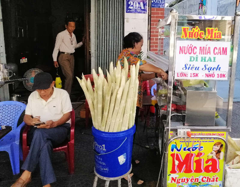 Sugar cane juice vendor preparing a juice on a sidewalk, Ho Chi Minh City, Vietnam. 